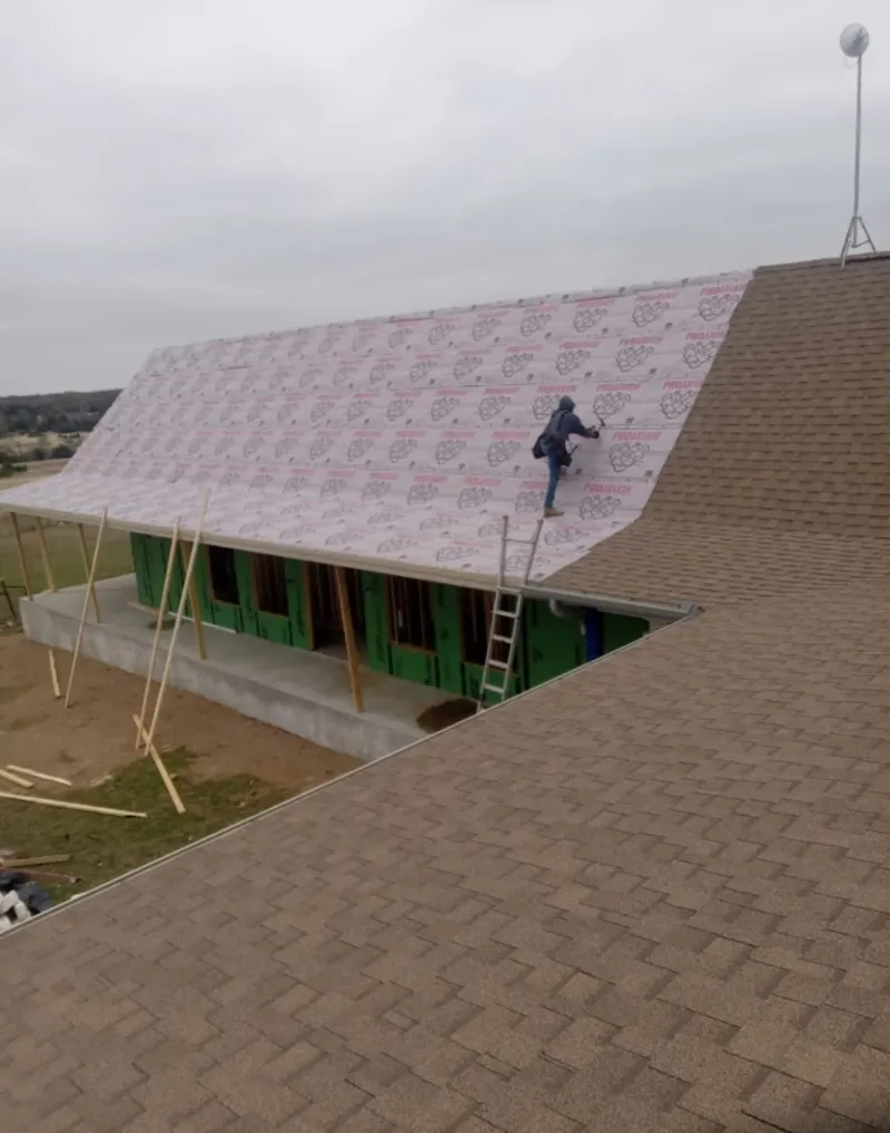Worker preparing underlayment for a metal roof installation in Idabel